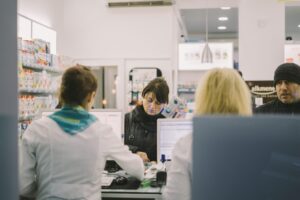 Inside view of a pharmacy, with pharmacists serving customers